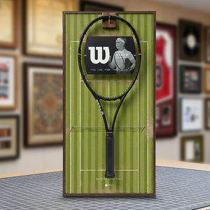 A ONE MAAY Wimbledon-inspired grass court tennis racket wall display mounted elegantly next to a wooden bookshelf in a home library, featuring a green side banner that reads "Wimbledon"