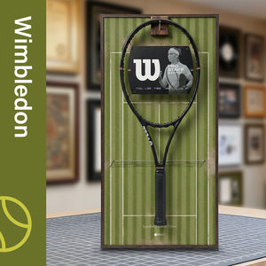 A ONE MAAY Wimbledon-inspired grass court tennis racket wall display mounted elegantly next to a wooden bookshelf in a home library, featuring a green side banner that reads "Wimbledon"