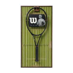 Front view of the ONE MAAY Wimbledon-inspired tennis racket wall display, featuring a dark wood colored aluminum frame and a green grass court background holding a black tennis racket.
