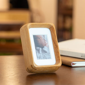 Wooden mini teak photo frame displaying a picture on a wooden surface. 2.2in x 3.3in. Polaroid fitting.