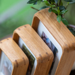 Wooden photo frames stacked together with a plant in the background