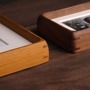 Two wooden picture frames on a wooden surface, teak and black walnut