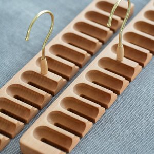 Wooden belt hanger with multiple hooks on a blue fabric background