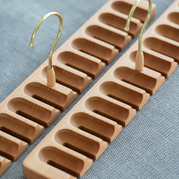 Wooden belt hanger with multiple hooks on a blue fabric background