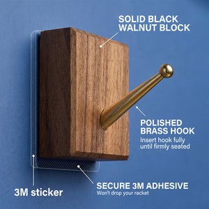 Detailed view of the solid black walnut block and polished brass hook with secure 3M adhesive used for mounting the racket on the ONE MAAY display