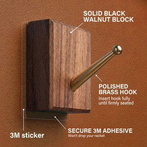 Detailed view of the solid black walnut block and polished brass hook with secure 3M adhesive used for mounting the racket on the ONE MAAY display.