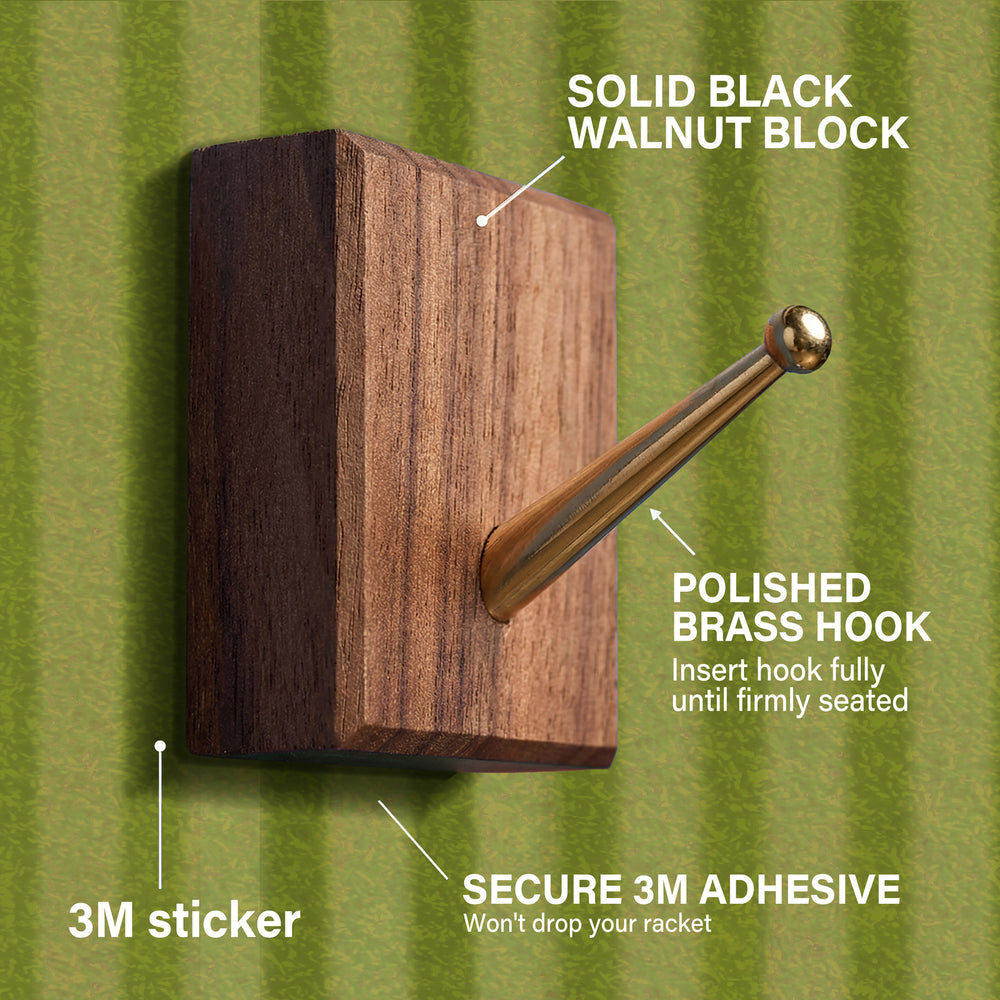 Detailed view of the solid black walnut block and polished brass hook with secure 3M adhesive used for mounting the racket on the ONE MAAY display.