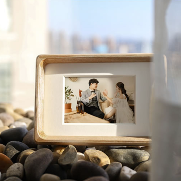 White ash framed artwork of a woman in a swimsuit by the water on a white background